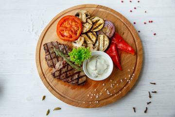Grilled beef steak served on a wooden Board with fried vegetables