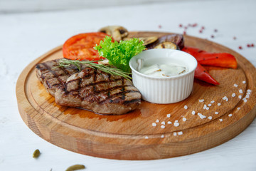Grilled beef steak served on a wooden Board with fried vegetables