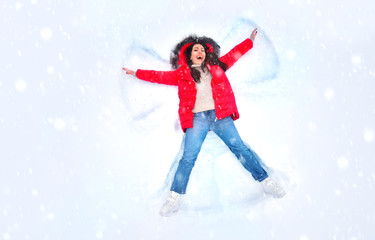 Naklejka na ściany i meble Snow angel concept. Happy woman enjoying first snow, lying in snow and making snow angel. Winter holidays and entertainment background.