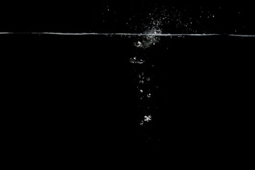 something falls into the water and causes seething and air bubbles on a black background for...
