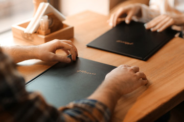 Young man with menu sitting in restaurant
