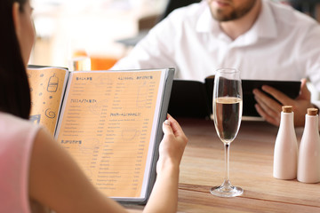 Obraz na płótnie Canvas Young couple with menu sitting in restaurant