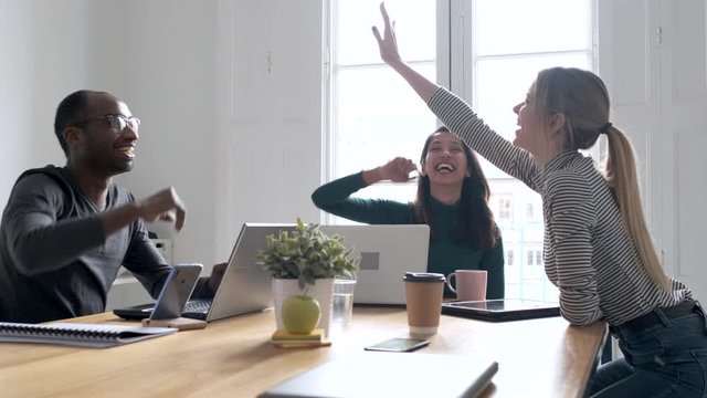 Video of group of successful young businesspeople holding up their right hands on coworking place.