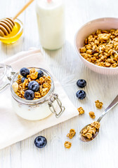 Homemade granola with blueberries in jar on white kitchen background