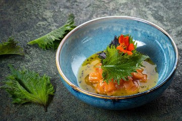 Salmon fillet ceviche with shiso leaves in a blue bowl. Fresh fish tartare