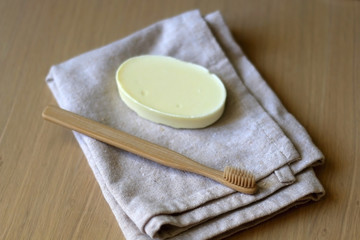 Linen dish cloth, sopa and bamboo toothbrush on wooden table. Selective focus.