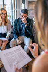 Tired businessman rubbing his eyes during a work meeting