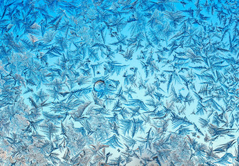 beautiful natural blue textured background with frosty pattern on glass on a clear winter morning