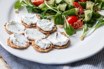 Fresh salad with tomato and cucumber and a side of crackers