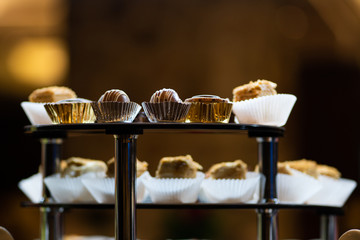 Mix of sweets, cakes, muffins. Beautifully laid out on a glass showcase. Setout.