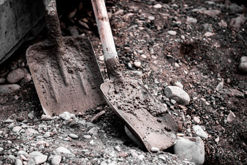 Dirty shovels on construction site. Old shovels with concrete and stones background. 