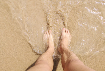 Feet of a man in the hot sand of the desert