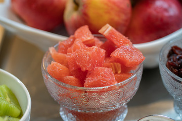 Slicing grapefruit on a table in a bowl. Against the background of other fruits.