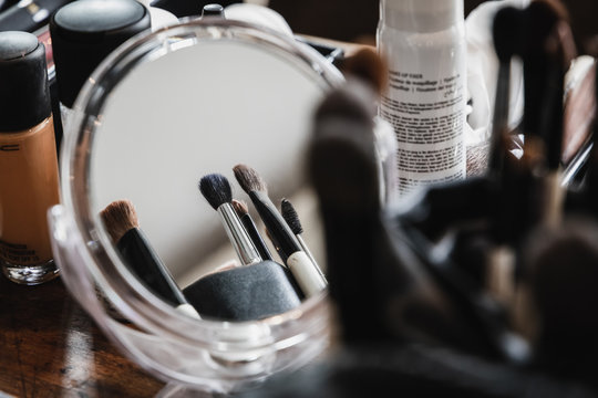 Makeup brushes in a cup in front of a mirror