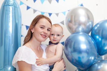 Portrait of happy mother and baby on the background of birthday decorations