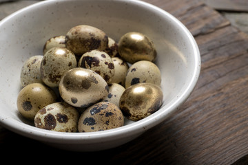 Easter quail eggs in a plate on an old wooden background, place for text