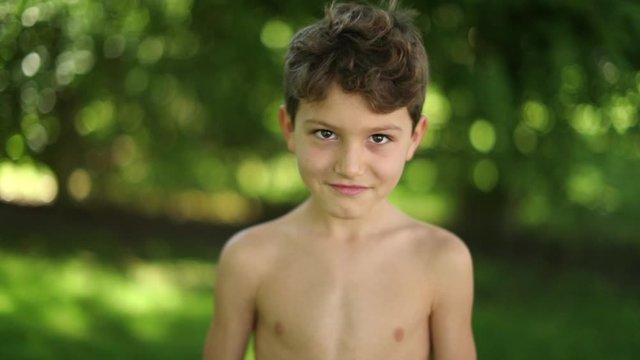 Child boy staring camera fixating with eyes. Portrait of kid looking to camera shirtless outside
