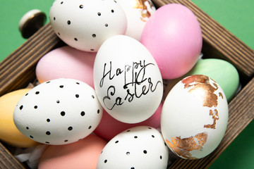Beautiful easter eggs in a box close-up on a green background, place for text, top view,