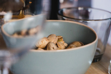 Pstachios in shell in a gray bwol  viewed from an empty wineglass