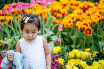 Cute little girl sitting at flower garden in Thailand.