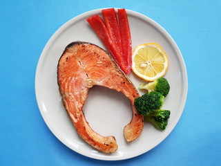  salmon with broccoli, sweet pepper and lemon  on white plate