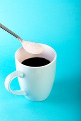 Morning coffee and a spoon with collagen powder on blue background.