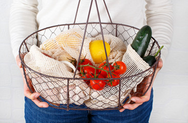 Woman keeps backet with fresh vegetables and fuits  in textile bags