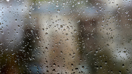 View of the city in a rainy day through a window covered with water drops
