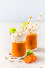 Pumpkin carrot orange smoothie with whipped cream. Selective focus, copy space.