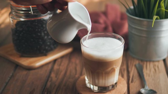 Process of making flat whites coffee. Close-up human hands using a press whisk milk in a white lush foam for cappuccino or latte at home,