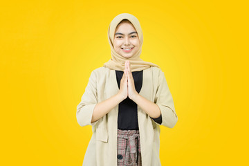 Young Asian woman wearing headscarf gives greeting hands at with big smile on her face