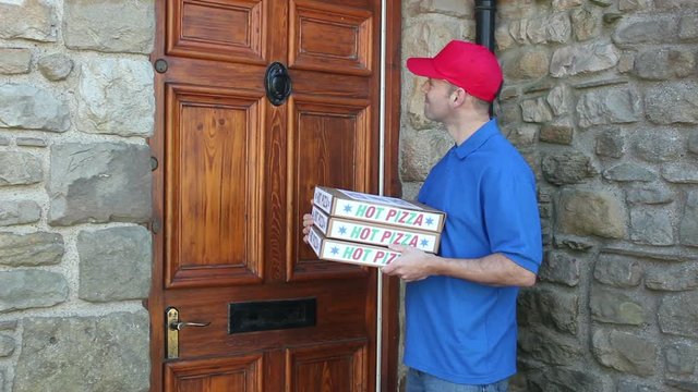 Pizza delivery to the home. The man hands over the warm boxes over to the female customer at her house front door. Tracking Shot. Stock Video Clip Footage