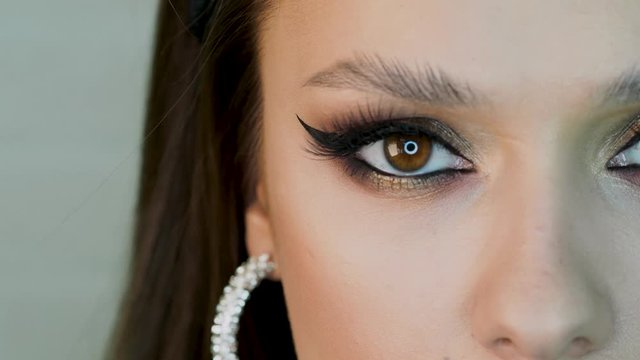 Glamorous bright eye makeup, women's eyes close-up. girl opens her eyes and looks at the camera, lush lashes and Golden eyeshadow