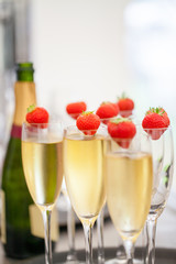 Glasses of sparkling wine or champagne and strawberry on a blurry background during some sort of festivity or celebration such as a wedding, borthday or newyear