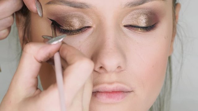 Beauty salon, makeup artist does evening makeup. Beautiful eyes with Golden eyeshadow