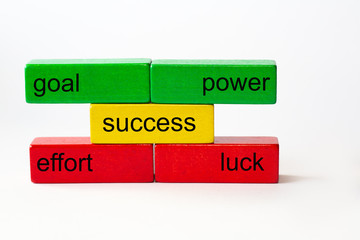 colored toy blocks with the words goal, power, effort, luck and the word success in the middle