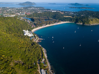 Fototapeta na wymiar beautiful aerial view of the white sand beach surrounded by green hills, yachts stand in the bay, small islands in the Adaman Sea, Nai Harn Beach, Phuket, Thailand