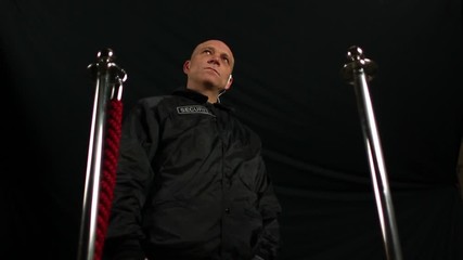 Bald Security Guard / Bouncer wearing black jacket opening a Rope Barrier at Nightclub - Skinhead -  Stock Video Clip Footage