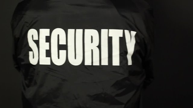 Security Guard / Bouncer wearing black jacket turns with folded arms - Unrecognisable person -  Stock Video Clip Footage