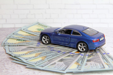 The tax on the car concept. Dollar banknotes and toy blue car.