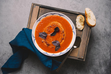 Homemade tomato soup on  wooden box-table in rustic bowl. The concept of cozy homecooked food. Dark photo