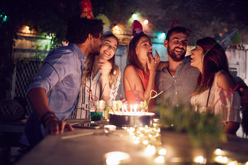 group of young friends celebrating a birthday in the club with cake and candles at night. birthday, party, fun, nighttime concept.