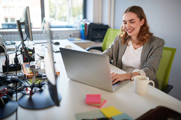 young business woman typing at laptop, working and smiling. loving your work concept