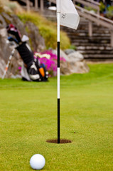 Obraz premium Golf ball on green with flag. Shallow depth of field. Focus on the flag.