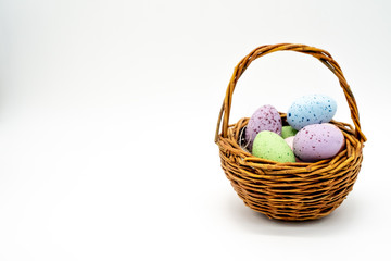 Mini woven easter basket with coloured speckled eggs isolated on