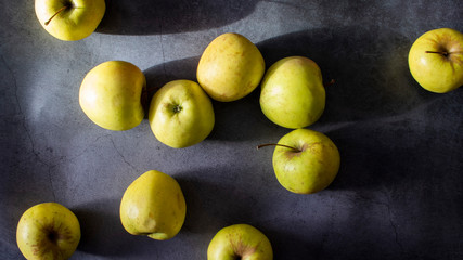 Yellow ripe apples scattered on a dark background - top view