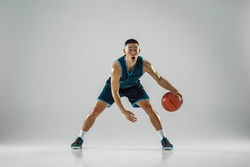 Obraz premium Young basketball player of team wearing sportwear training, practicing in action, motion in run isolated on white background. Concept of sport, movement, energy and dynamic, healthy lifestyle.