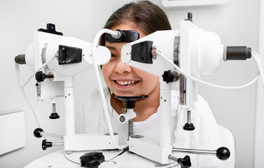 Mixed race girl near synoptophore to check her eyes. Diagnosis and treatment of strabismus in a vision clinic