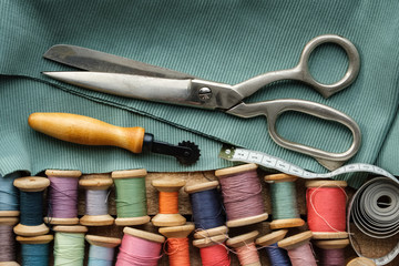 Sewing items: retro tailoring scissors, measuring tape, wooden spools of threads, cutting knife and...