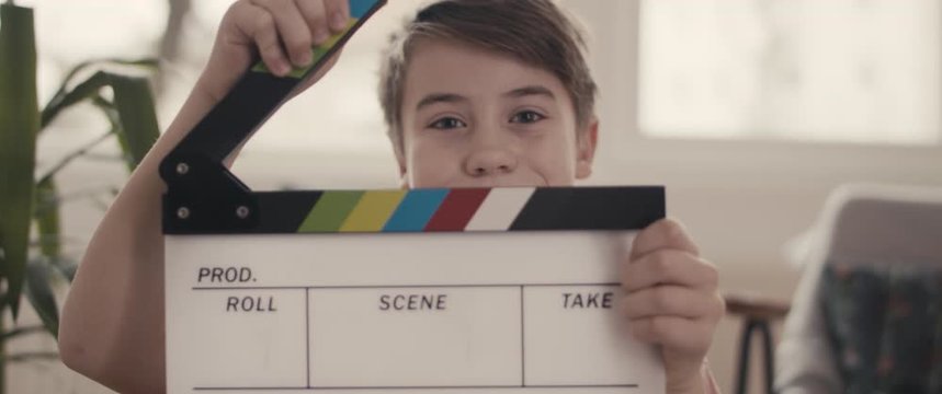 Portrait of young boy with clapper board on film set close up widescreen cinemascope